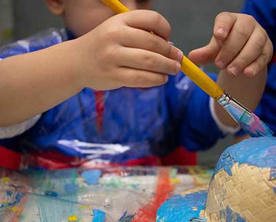 Criança pintando peça decorativa junina - Educação Infantil Uniepre