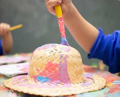 Criança pintando peça decorativa junina - Educação Infantil Uniepre