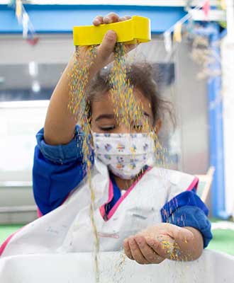 Criança explorando flocos coloridos - Ensino Fundamental Uniepre