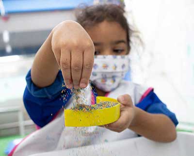 Criança explorando flocos coloridos - Ensino Fundamental Uniepre